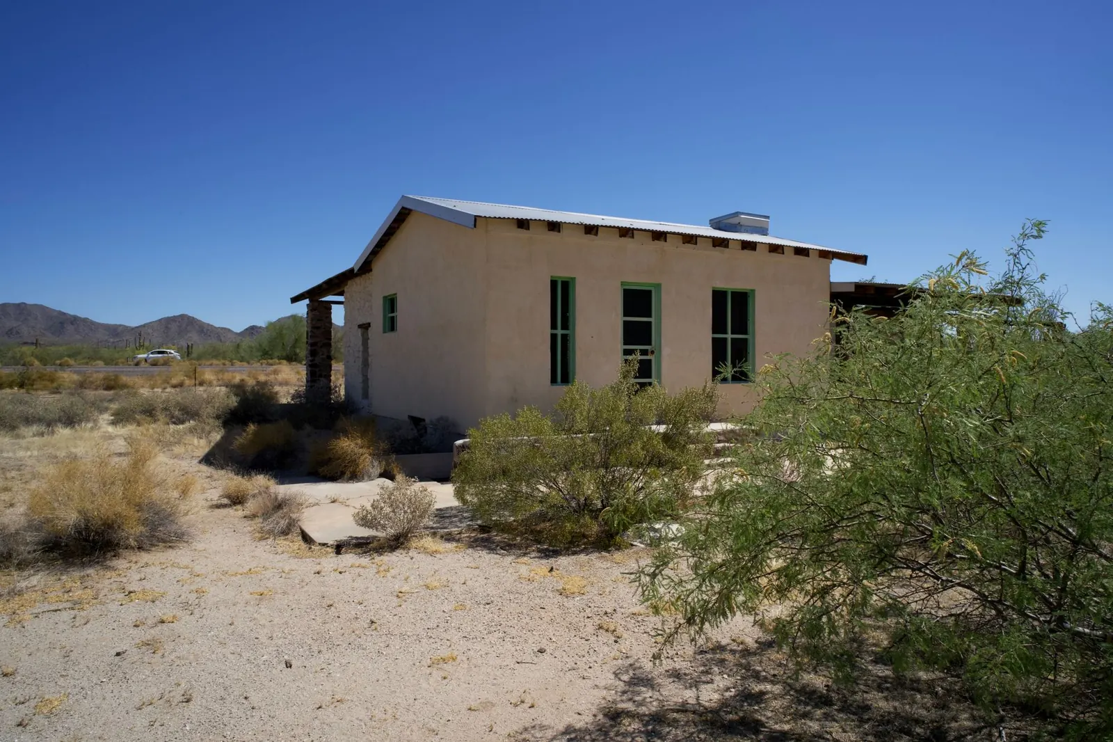 Desert home with a metal roof and mesquite trees