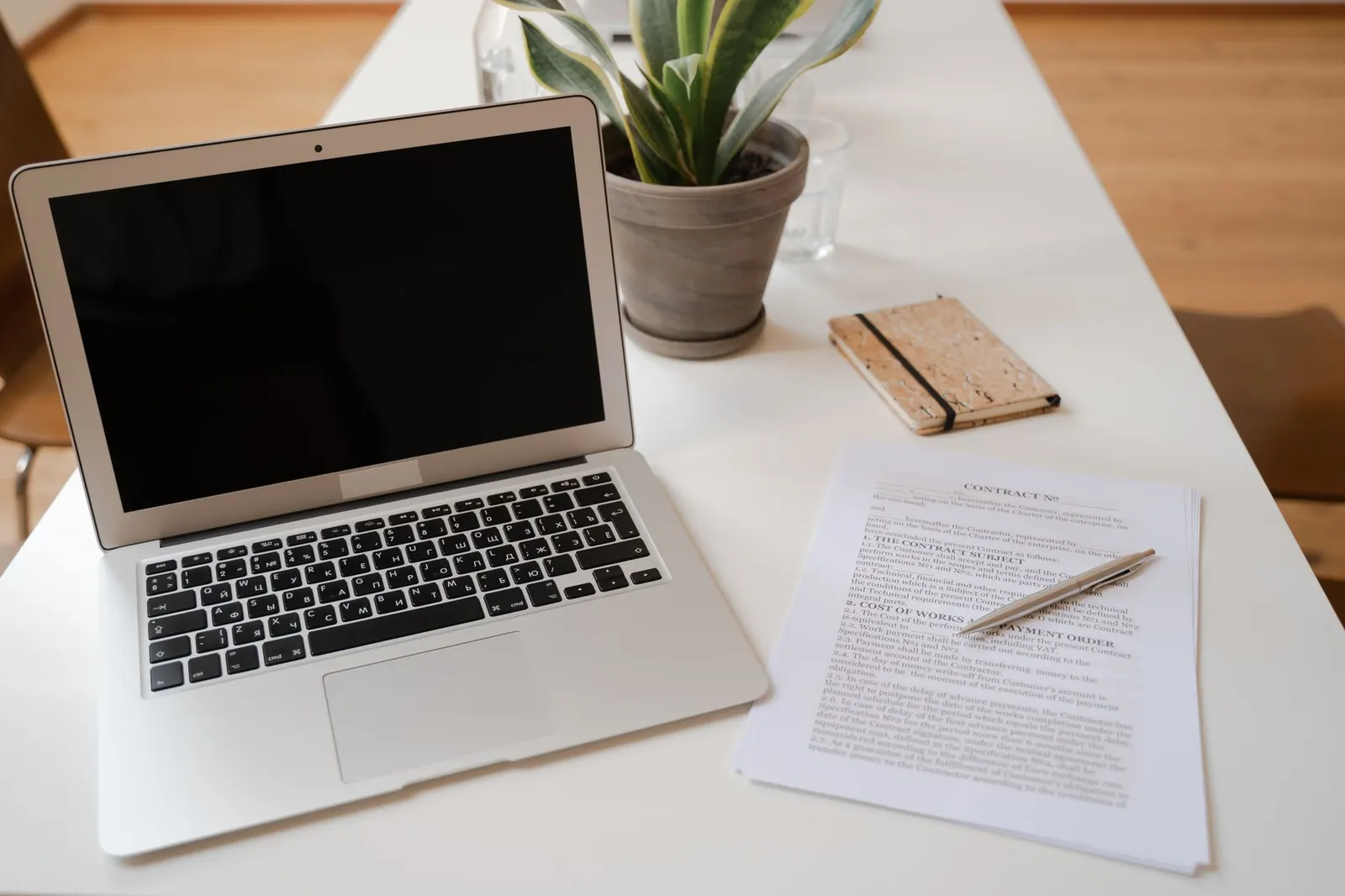 Laptop, documents and a plant on an office desk